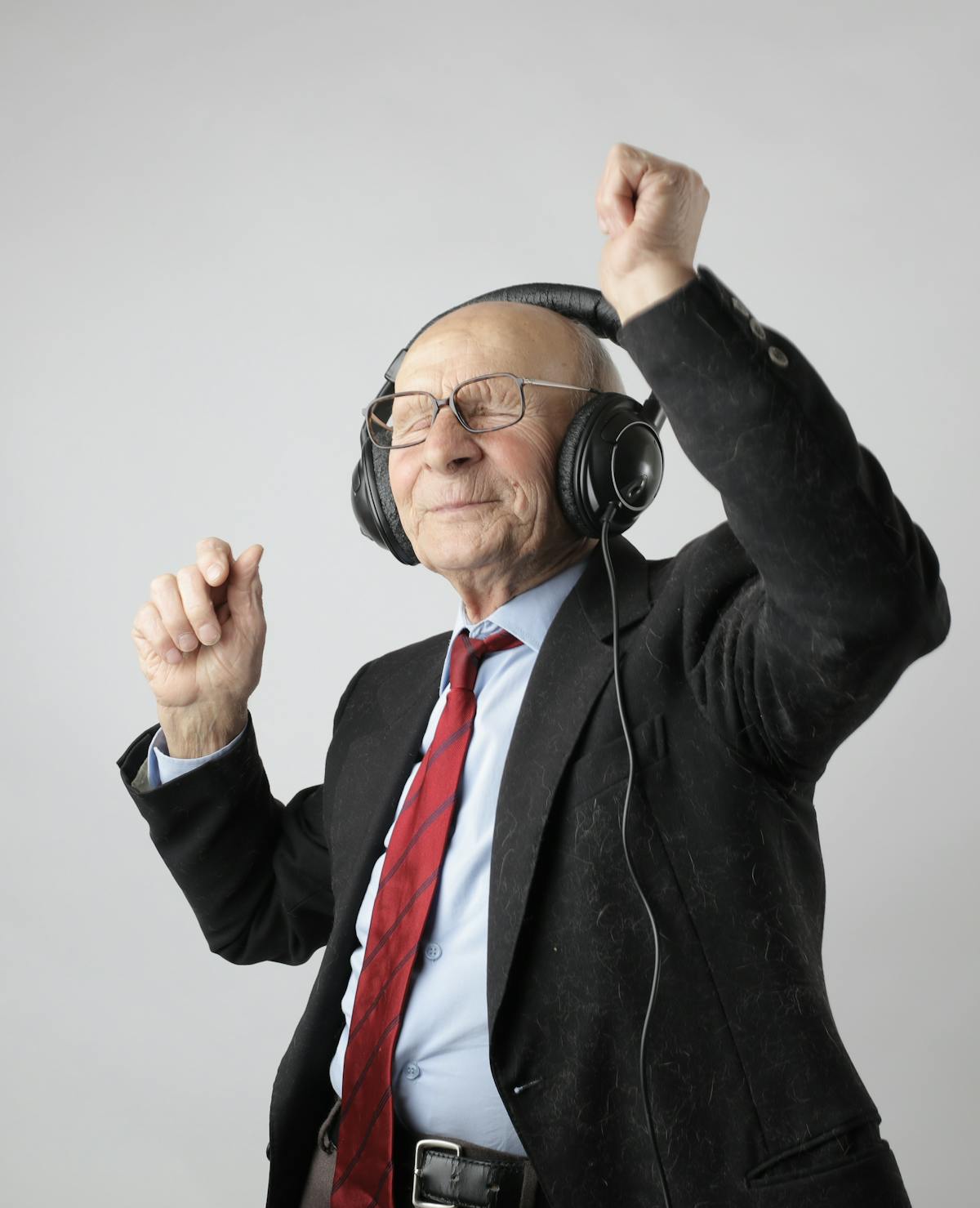 Älterer Herr im Anzug genießt Musik mit Kopfhörern und tanzt mit viel Lebensfreude